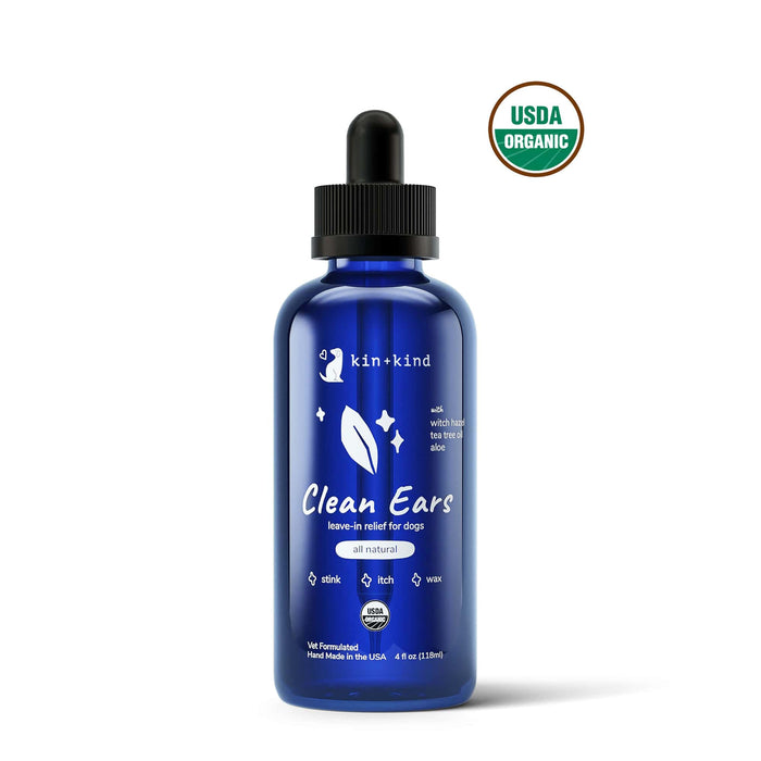 A blue bottle of kin+kind Organic Clean Ears leave-in dog ear cleaner with a dropper lid, featuring a label that highlights USDA-certified organic, all-natural ingredients designed to relieve stink, itch, and wax buildup. Vet formulated for optimal ear care.