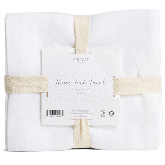A set of three white Organic Cotton Flour Sack Towels by Grove Co., made from 100% organic cotton, ideal for kitchen use, wrapped with beige straps and labeled Grove Collaborative.