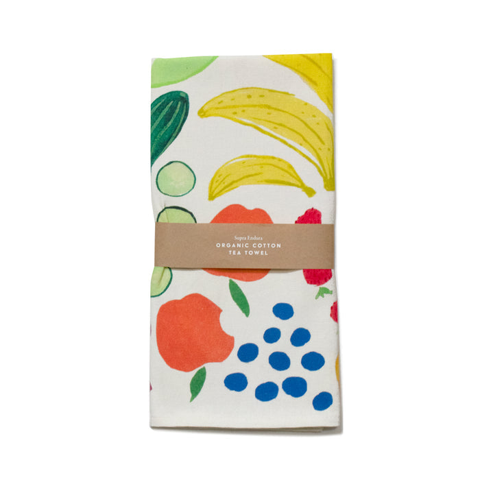 Supra Enduras Organic Cotton Tea Towel displays vibrant fruit illustrations of bananas, strawberries, oranges, and blueberries. Made from durable organic cotton, its folded and wrapped with a brown paper band labeled with its name to showcase its original artwork.