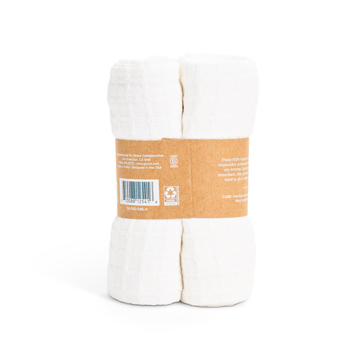 Two rolls of Grove Co. Organic Cotton Textured Kitchen Towels, resembling absorbent quick-drying towels, are bundled with a brown paper label bearing product info and care instructions. The soft fabric is compactly stacked vertically.