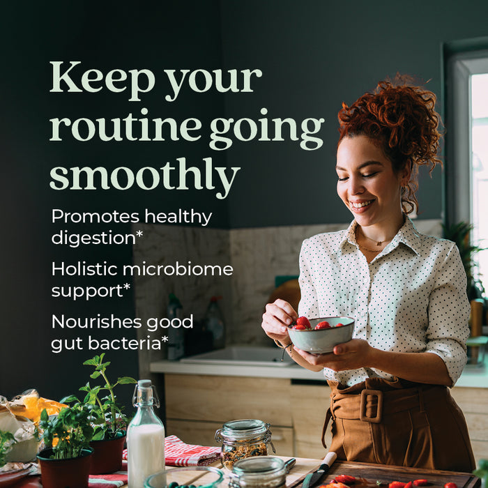 A woman prepares food in a kitchen while smiling. Text on the image reads: "Keep your routine going smoothly. Promotes healthy digestion*. Holistic microbiome support*. Nourishes good gut bacteria*.
