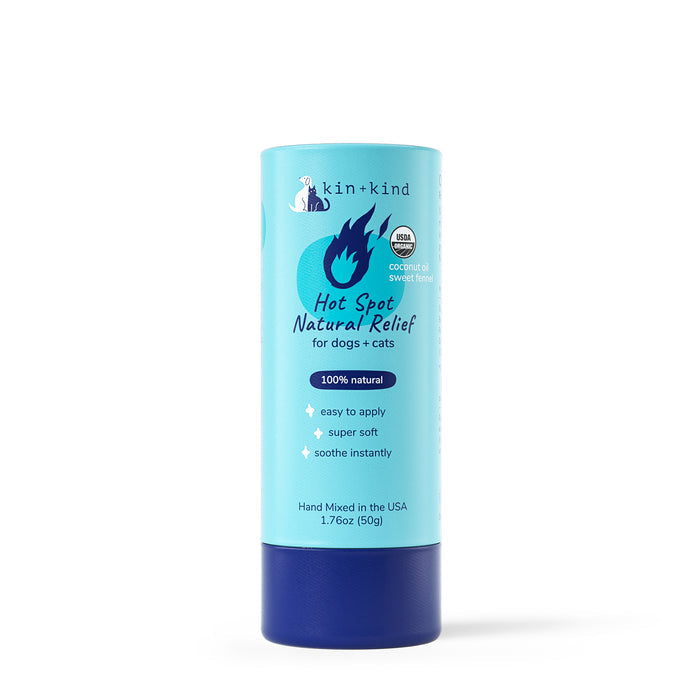 The kin+kind Organic Hot Spot Relief Stick for Dogs & Cats comes in a 1.76oz (50g) cylindrical container with light blue packaging, dark blue and white text, and a flame icon. Its perfect for irritated skin relief with 100% natural ingredients and a coconut & sweet fennel scent.