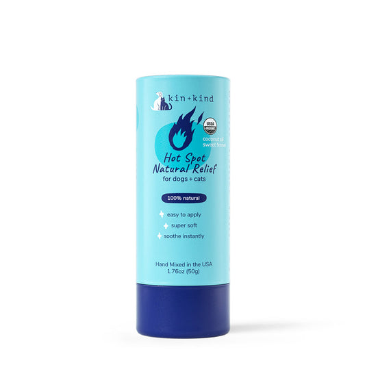 The kin+kind Organic Hot Spot Relief Stick for Dogs & Cats comes in a 1.76oz (50g) cylindrical container with light blue packaging, dark blue and white text, and a flame icon. Its perfect for irritated skin relief with 100% natural ingredients and a coconut & sweet fennel scent.