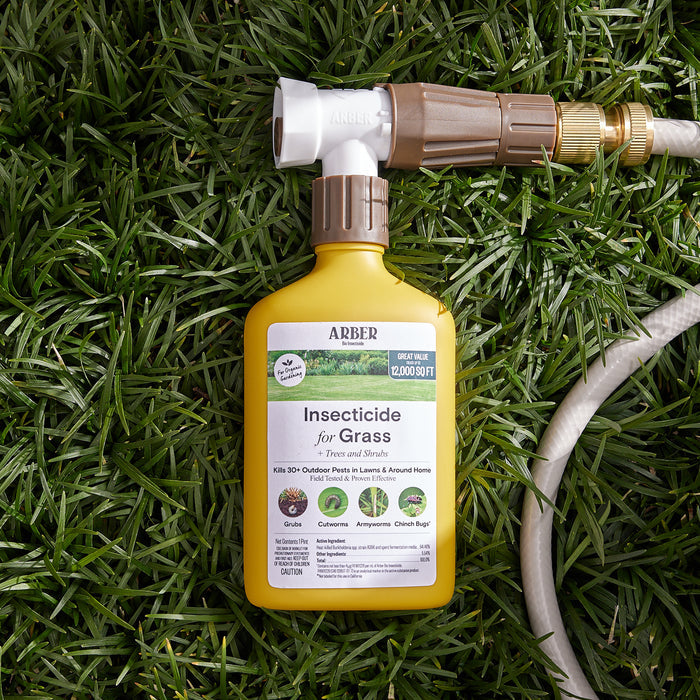 A bottle of Arber Organic Insecticide for Lawn, Tree, and Shrub, RTS sits on lush green grass. The label features its chemical-free formula, covering 12,000 sq. ft. to combat pests like grubs, caterpillars, and chinch bugs. A hose is partially visible beside the bottle.