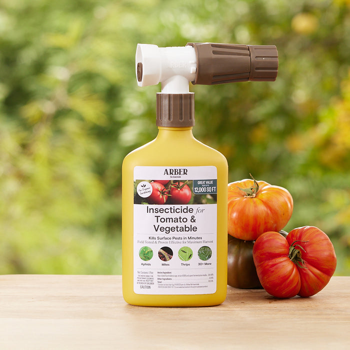 A bottle of Arbers Organic Insecticide for Tomato Fruit & Vegetables RTS, ideal for vegetable garden pest control, rests on a wooden table with a spray attachment. Behind it, vibrant heirloom tomatoes in red and purple stand against lush, blurred greenery.