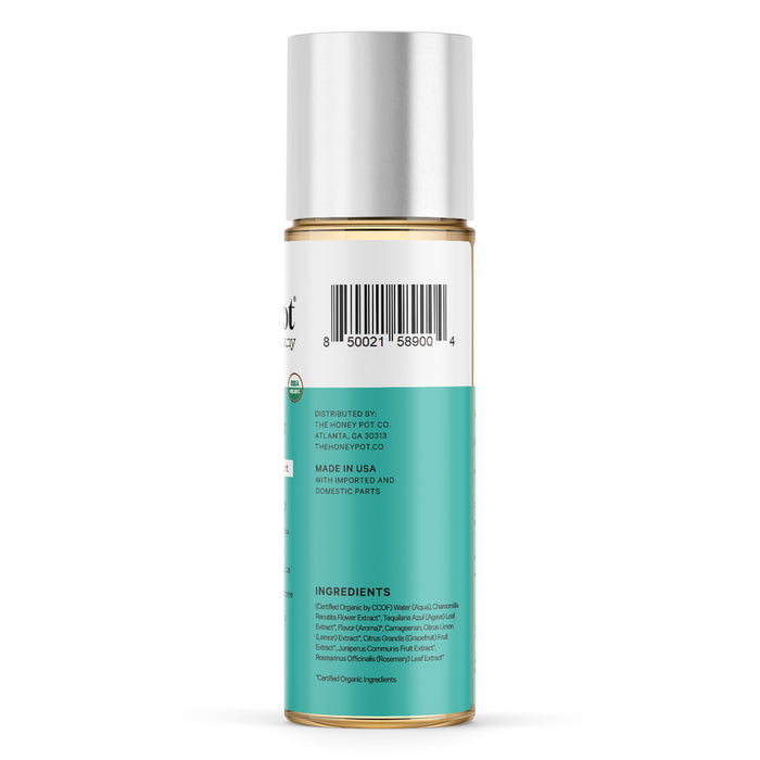 A cylindrical canister with a silver cap has a teal label showing a barcode, distribution details, and ingredients list. This Organic Lubricant by The Honeypot Company contains Agave Extract and is made in the USA with imported and domestic parts.