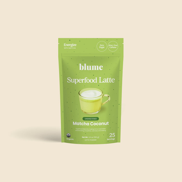 A green pouch of blume’s Organic Matcha Coconut Latte Powder stands upright on a cream background. This unsweetened, antioxidant-rich superfood powder is organic, offers 25 servings, and the packaging features a green latte cup.