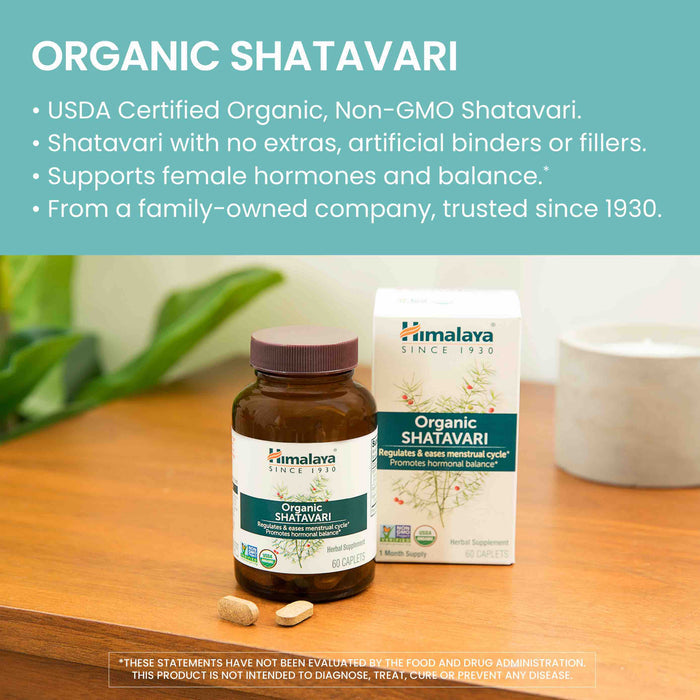A bottle and box of Himalaya Organic Shatavari supplements on a wooden surface. The packaging highlights key benefits like hormone support and being USDA Certified Organic. Two capsules are placed beside the bottle.