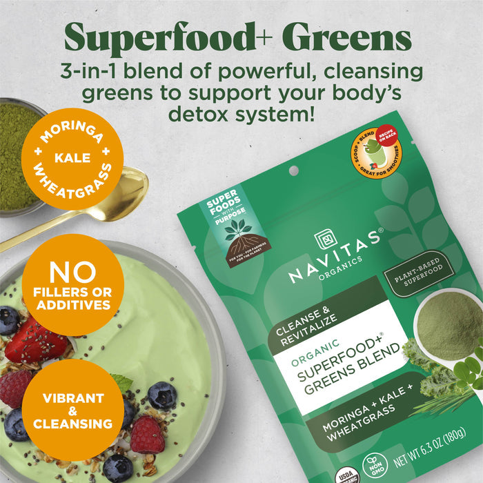 Packaging of Navitas Organics Superfood+ Greens blend with moringa, kale, and wheatgrass. The pack is green and labeled "3-in-1 blend," shown beside a bowl of green smoothie topped with berries. Text highlights its detox benefits and natural ingredients.