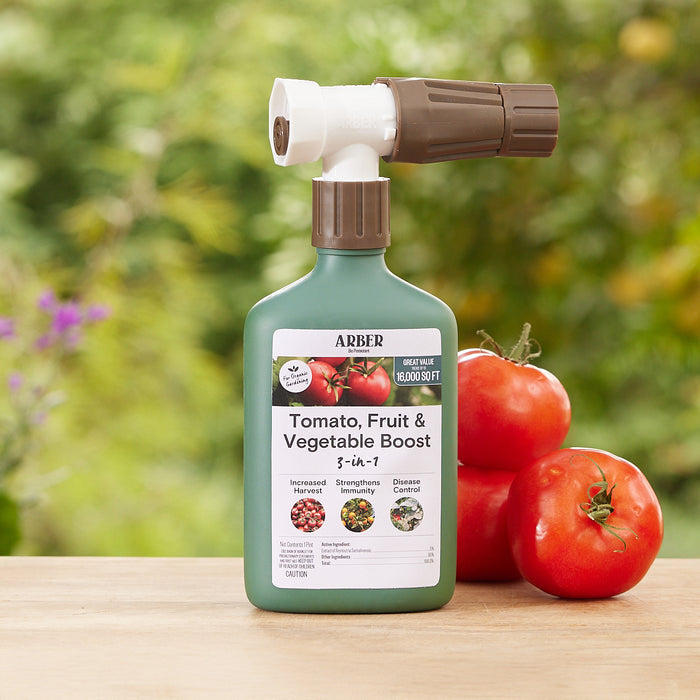 A green bottle labeled Arber Organic Tomato, Fruit & Vegetables 3-in-1 Boost RTS with a spray attachment sits on a wooden surface. Nearby, two ripe tomatoes bask in the gardens glow. This formula claims to enhance harvests in any thriving garden setting.