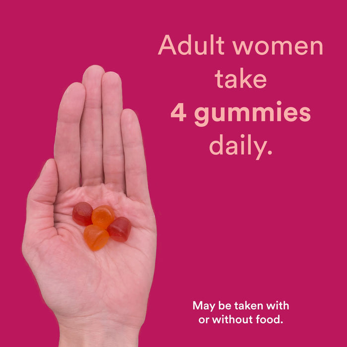 A hand holds four multicolored gummies against a pink background. Text reads, Adult women take 4 SmartyPants Organic Womens Multi & Omegas Gummies daily. Smaller text says, May be taken with or without food.