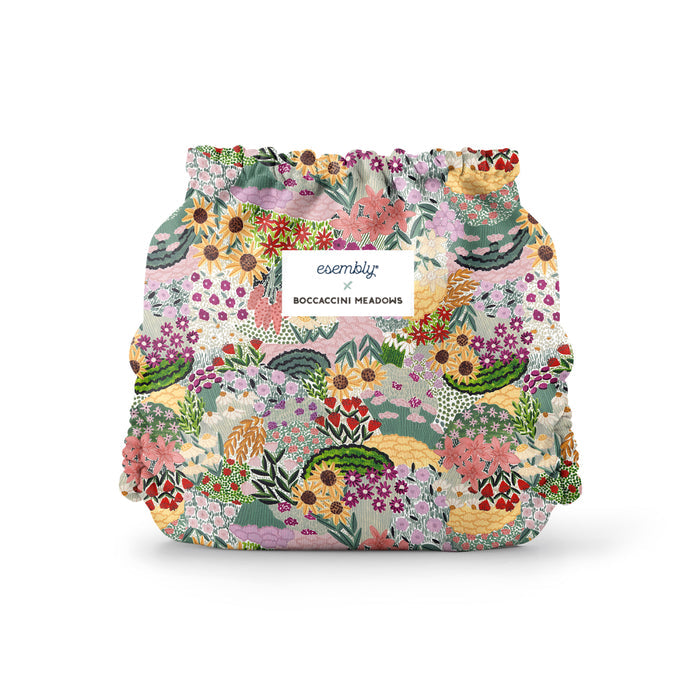 The Esembly Baby Outer Diaper Cover + Swim Diaper, Size 2 is crafted from colorful, 100% OEKO-TEX certified recycled fabric adorned with floral patterns. A white label reads Esembly x Boccaccini Meadows, highlighting its stylish, reusable nature.