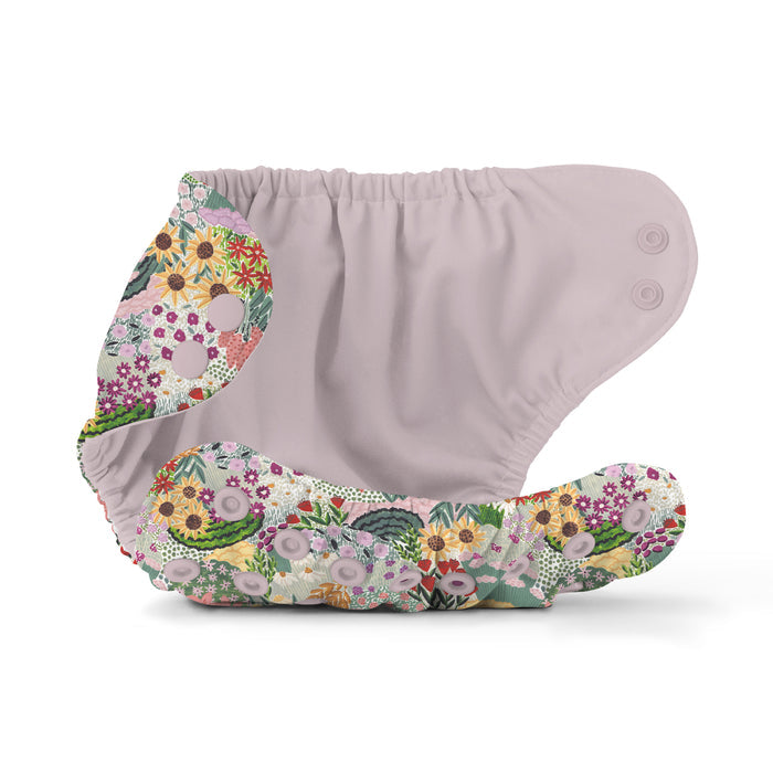The Esembly Baby Outer Diaper Cover + Swim Diaper, Size 2, features a vibrant floral pattern with snaps on the front. Its top part is plain light gray, while the rest showcases flowers in green, purple, yellow, and red shades. Made from 100% OEKO-TEX Certified Recycled Fabric, it combines function with flair.