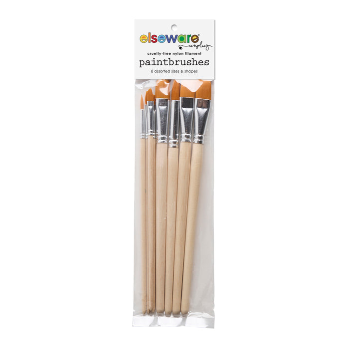 A clear plastic package holds six wooden-handled, cruelty-free paintbrushes with flat brown bristles. The top label says "Elseware Unplug Paintbrush Set—6 assorted sizes & shapes, perfect for watercolor and acrylic.
