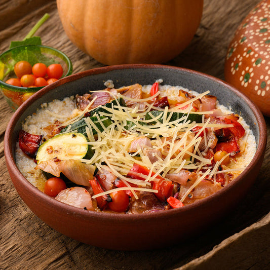 bowl of polenta with roasted veggies and shredded parmesan cheese.
