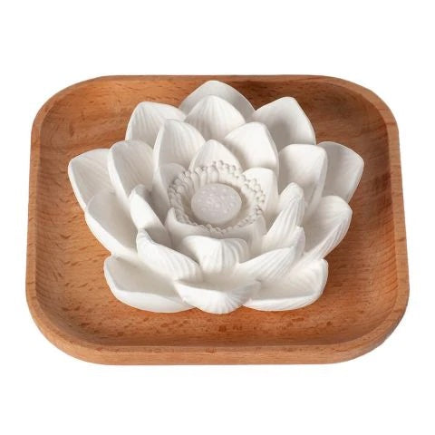 A white, intricately detailed lotus-shaped soap rests on a natural beech wood tray, its delicately carved petals reminiscent of Plant Therapy’s Passive Lotus Diffuser.