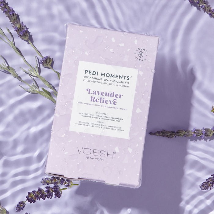 A flat-lay of VOESH New Yorks Pedi Moments kit showcases a luxurious at-home spa experience. The light purple Lavender Relieve packaging is adorned with lavender sprigs and includes a nail file for perfect pampering.