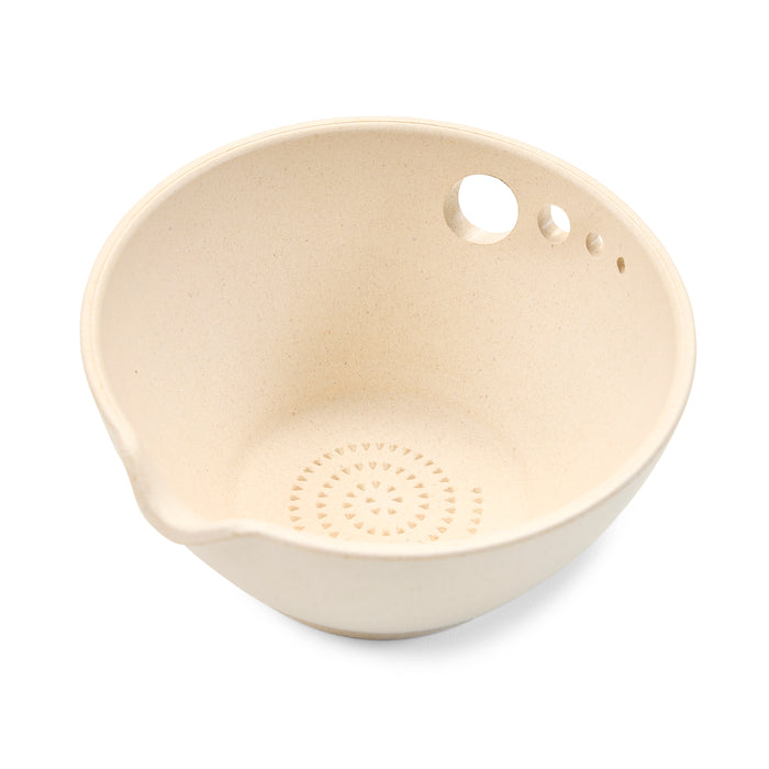 The Peel, Grate & Prep Dish by Modern Sprout is a beige mixing bowl with a textured bottom and pouring spout, ideal for any prep task. Its rim includes three small holes for hanging or draining.
