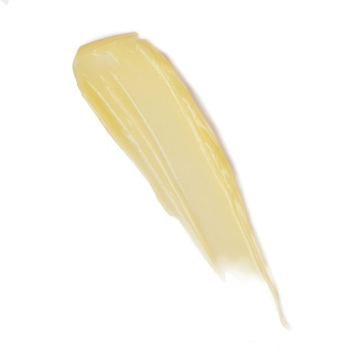 A streak of creamy yellow substance, echoing Kari Grans Peppermint Lip Whip Treatment Balm, is applied on a white background. It reveals a smooth, glossy texture with visible brush strokes, capturing the essence of natural lip care.