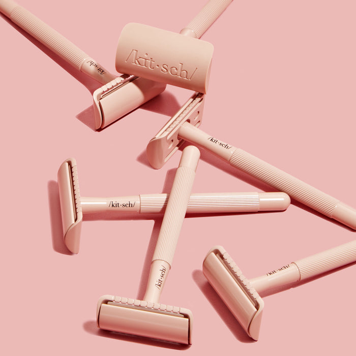 Kitschs Perfect Glide Safety Razor, with stainless steel blades and a roller, is artistically arranged on a pink background. The sleek handle, smooth roller, and Kitsch Solid Shave Butter create a visually cohesive scene.