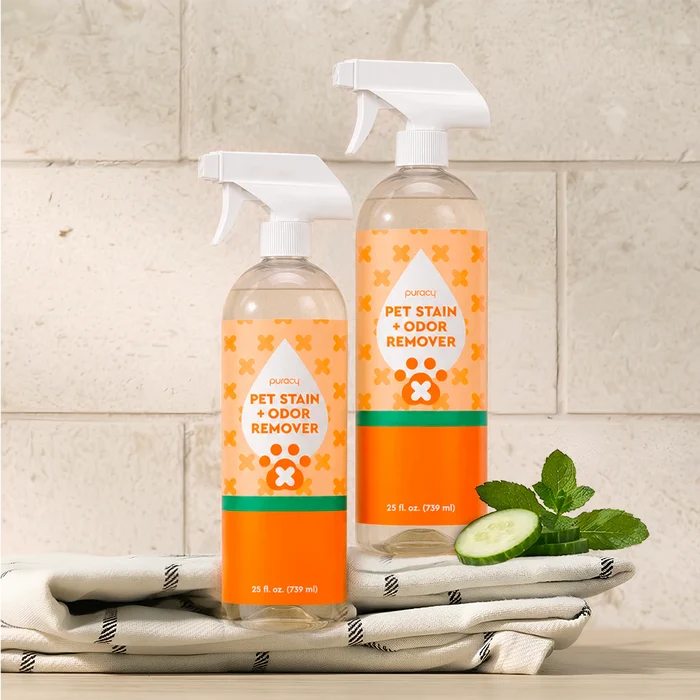 Two bottles of Pet Stain & Odor Remover on towels, with mint and cucumber.