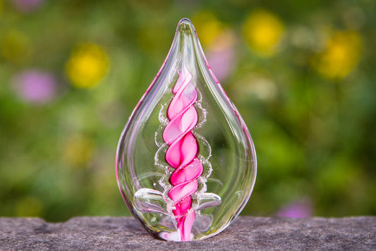 Clear glass memorial flame with a pink spiral interior containing cremation ashes