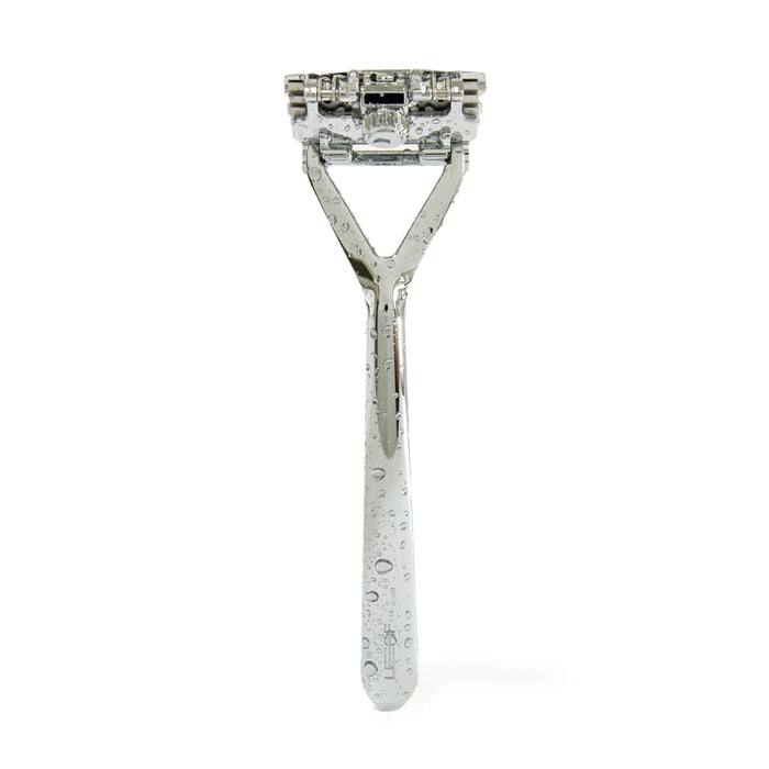The Plastic Free Razor by Leaf Shave stands tall, its stainless steel construction glistening with water droplets. The sleek handle and multi-blade design are gentle on sensitive skin, creating a striking visual against a plain white background.