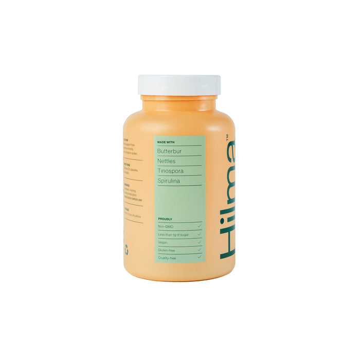 A yellow-orange supplement bottle with a white cap labeled Pollen Defense by Hilma offers sinus support through natural herbs. Ingredients like Butterbur and Spirulina are highlighted, along with claims of being non-GMO, low sugar, vegan, gluten-free, and free of artificial dyes.