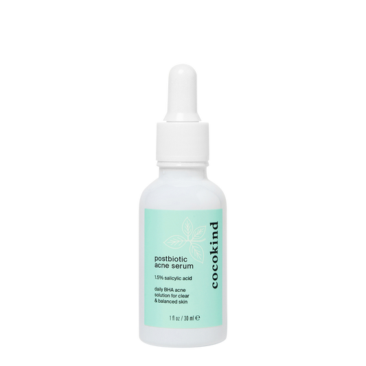 The Cocokind Postbiotic Acne Serum, featuring 1.5% salicylic acid, has a light green label and white dropper cap, and targets clogged pores for clearer skin.
