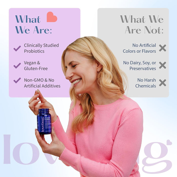A smiling woman in a pink sweater holds a blue bottle of Lovebugs Postnatal Probiotic - Lactation Blend, featuring vegan, gluten-free, non-GMO ingredients and probiotic strains for lactation—free from dairy, soy, artificial colors, and harsh chemicals.