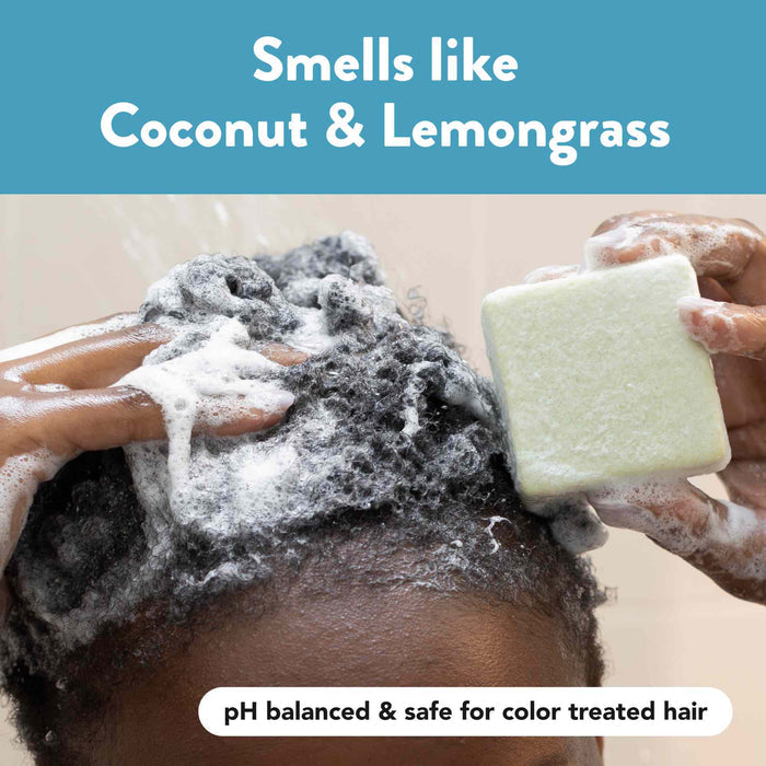A person lathers their curly hair with a foamy, white soap bar. The image text reads "Smells like Coconut &amp; Lemongrass" and "pH balanced &amp; safe for color treated hair." The soap bar and hands are visible against a clean background.