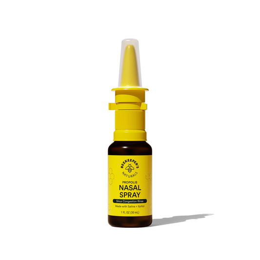 Beekeepers Naturals Propolis Nasal Spray comes in a yellow and brown bottle with a bee logo. It uses Saline + Xylitol to soothe nasal passages and relieve sinus congestion, set against a plain white background.