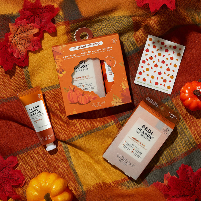 Flat lay of VOESH Pumpkin Pie Duo with Nail Stickers on a plaid blanket, accented by autumn leaves and mini pumpkins, evokes a cozy fall vibe with a warm pumpkin pie scent.