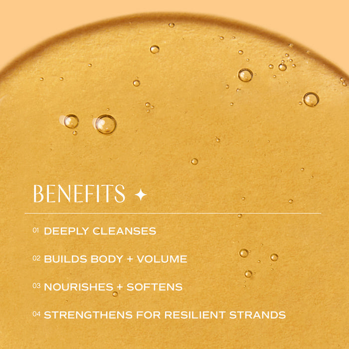 A golden, amber-tinted liquid with small bubbles is displayed as a background. Text overlaid reads: "Benefits - 1. Deeply cleanses. 2. Builds body + volume. 3. Nourishes + softens. 4. Strengthens for resilient strands.
