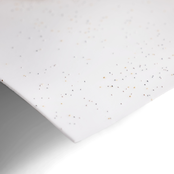 Close-up of a curved white sheet speckled with black and tan hues, reflecting Grove Co.s PurePower Enzymatic Laundry Detergent Sheets—bio-based cleaners designed to lower carbon emissions, set against a white backdrop.