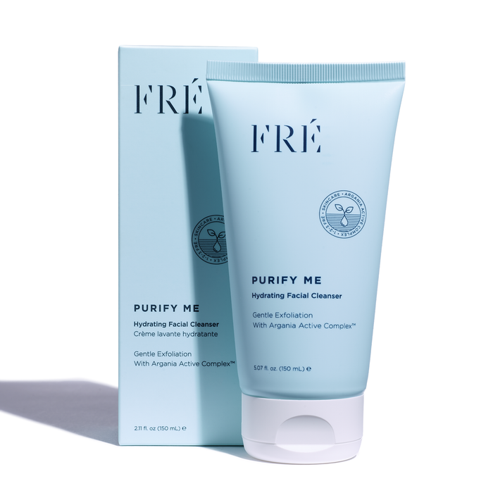 A blue tube of FRÉ Skincares PURIFY ME Hydrating Facial Cleanser is placed in front of its box, highlighting gentle exfoliation and Argania Active Complex for pore minimization. The cleanser contains 5.07 fl oz (150 mL).