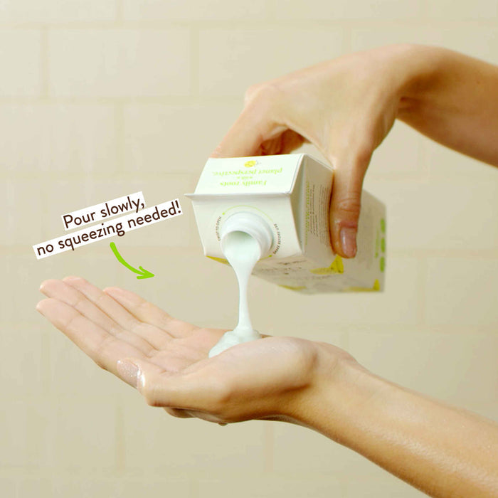A person's hand pouring a creamy white lotion from a carton into their other open hand. The carton has green and white packaging. A message next to it reads, "Pour slowly, no squeezing needed!" The background is a light, blurred surface.