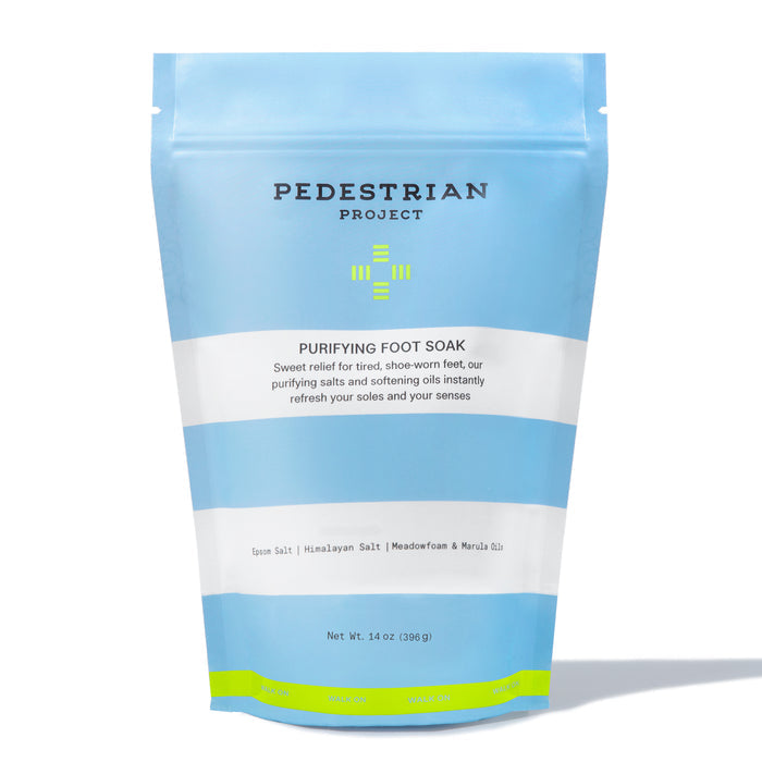 Pedestrian Projects Purifying Foot Soak comes in a blue and white package. This vegan blend contains Epsom Salt, Himalayan Salt, Meadowfoam & Marula Oil to detoxify and relieve tired feet. Net weight: 14 oz (396 g).