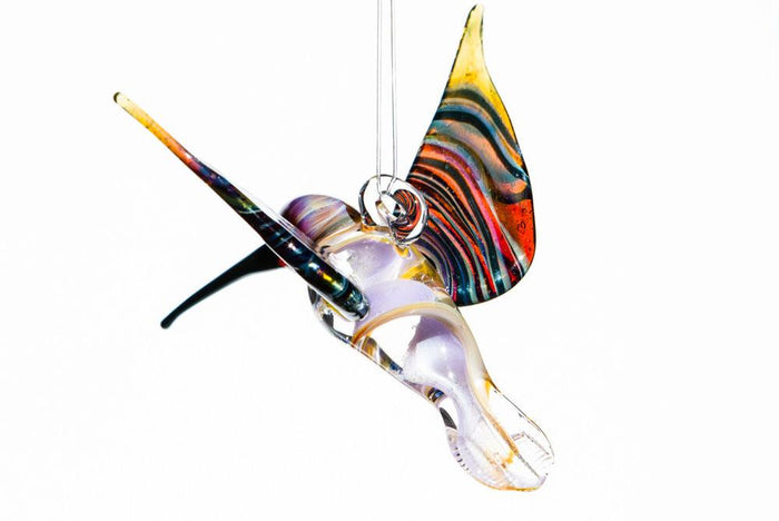 Purple and amber glass hummingbird pendant with cremains swirled through the body and a hanging glass hook.