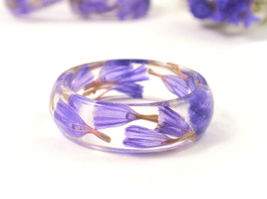 Clear resin ring embedded with purple flowers and cremation ash
