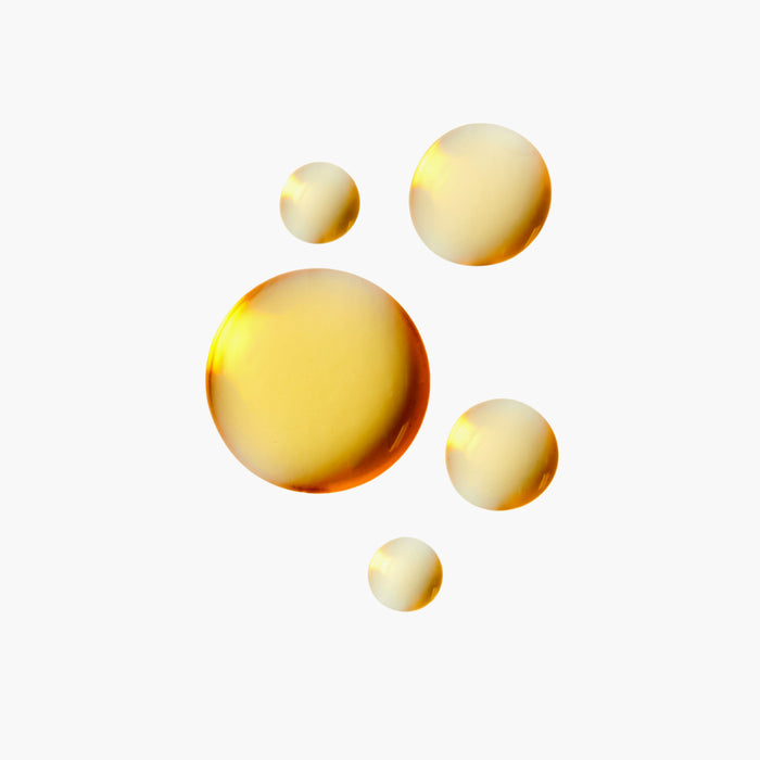 Five golden, translucent droplets of R7 Complex Facial Oil by Rooted Beauty rest on a white backdrop. Rich in antioxidants and varying in size, they catch the light and promise deep hydration and vitality.