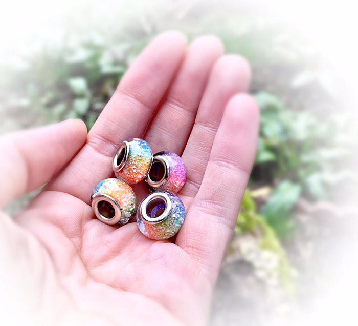 Rainbow cremation ash beads held in the palm with silver bracelet cores