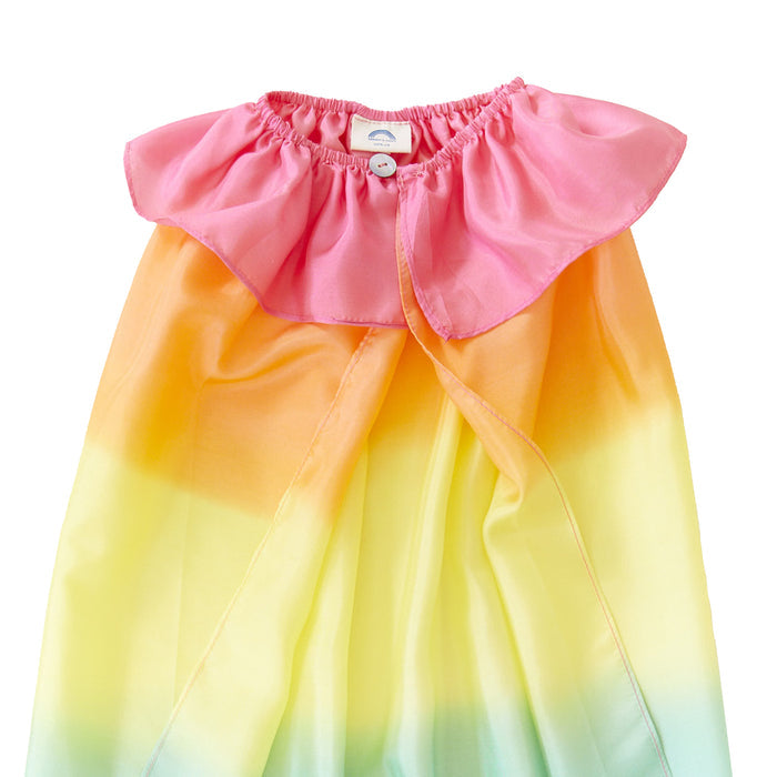 The Rainbow Cape by Sarahs Silks is perfect for dress-up play, featuring a pink ruffled collar and a gradient of orange to yellow to light green. Its made of silk with a single button closure at the top.