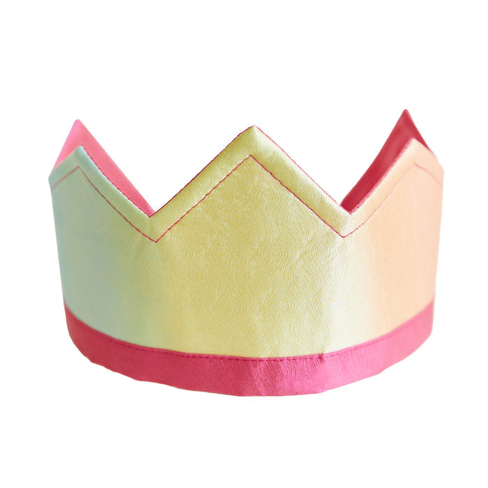 The Rainbow Crown by Sarahs Silks, perfect for imaginative play, features pastel pink, yellow, and green with a zigzag top. A bright pink band accents the base. Made from subtly textured fabric, this colorful crown is ideal for dress-up and creative adventures.