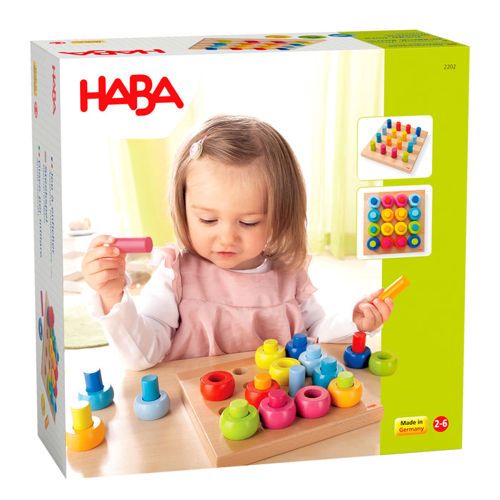 The packaging of the Rainbow Whirls Wooden Sorting and Stacking Game by HABA shows a young child enjoying the colorful set, emphasizing its value for fine motor development. The box features the HABA logo, vibrant pegs and rings images, and notes that this Montessori toy is made in Germany for ages 2-6.