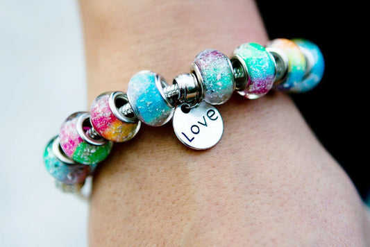 Rainbow's Bridge bracelet with eight colorful ash beads and a silver Love charm