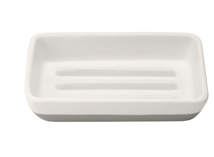 The Full Circles Raise the Bar Soap Holder, a white rectangular ceramic piece with ridged grooves, adds elegance and complements eco-friendly living—ideal for sustainability enthusiasts.