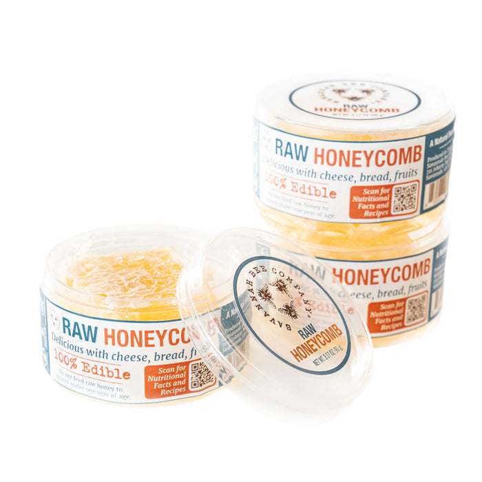 The Savannah Bee Companys Raw Honeycomb Picnic Round includes three plastic containers filled with raw honeycomb. Labeled as 100% edible, they suggest pairing with cheese, bread, and fruits for an energizing snack. The bee logo and clear lids complete the presentation.