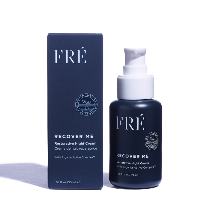A bottle and box of FRÉ Skincares RECOVER ME Restorative Night Cream are side by side. The dark blue items with white text feature the skin-repairing Argania Active Complex™ and a handy pump dispenser for easy nighttime rejuvenation.