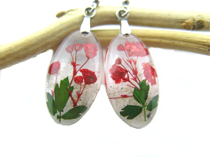 Oval clear resin earrings with red flowers and green leaves on silver ear wires